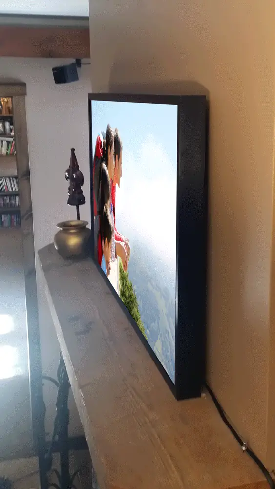A Nimbus frame resting on a wooden ledge in a hallway, displaying a family photograph