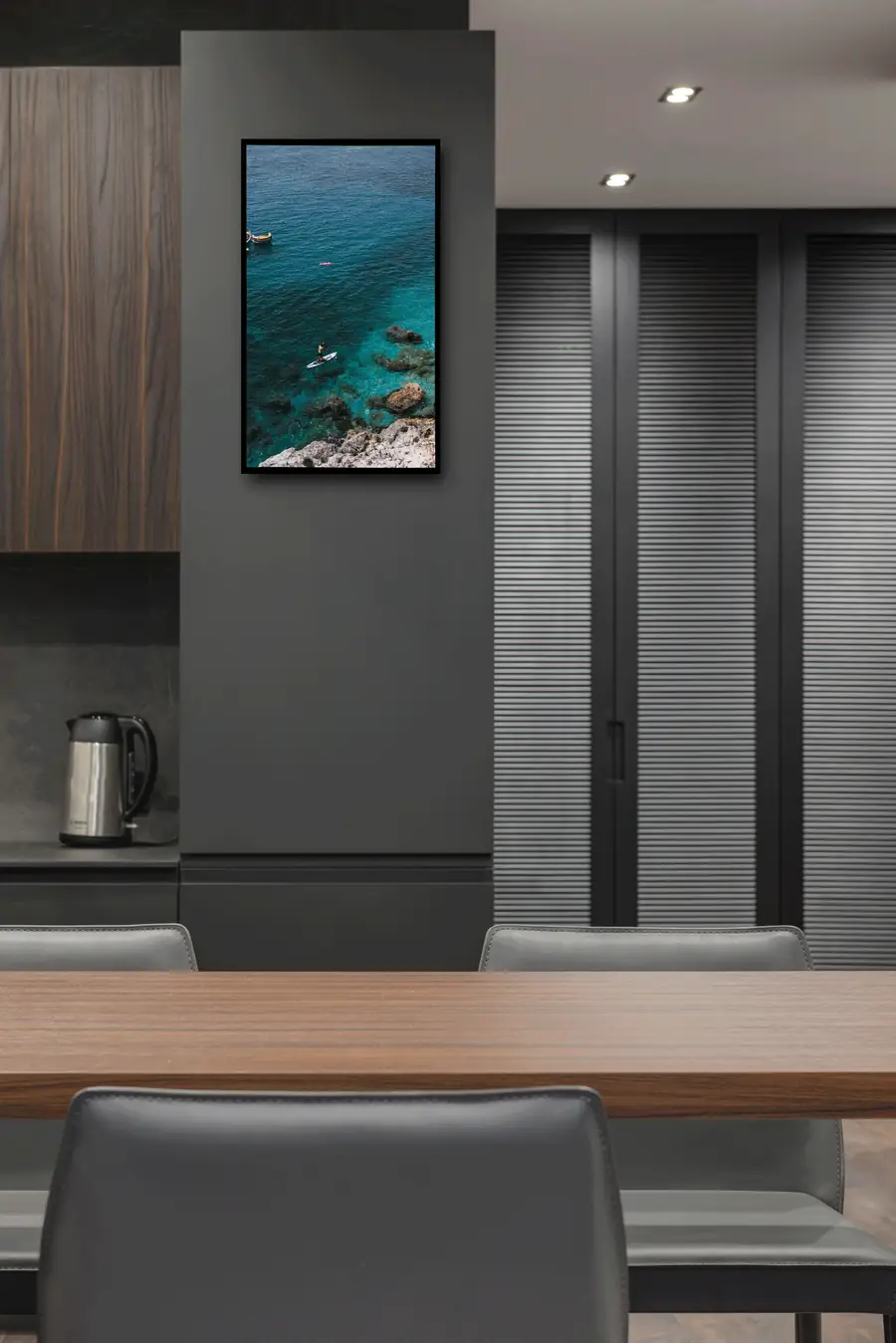 A Nimbus frame on the wall of a modern kitchen, displaying an aerial photograph of a turquoise coastline